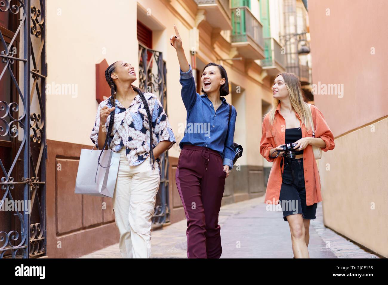 Deliziose Signore multirazziali che guardano contro il muro della città Foto Stock