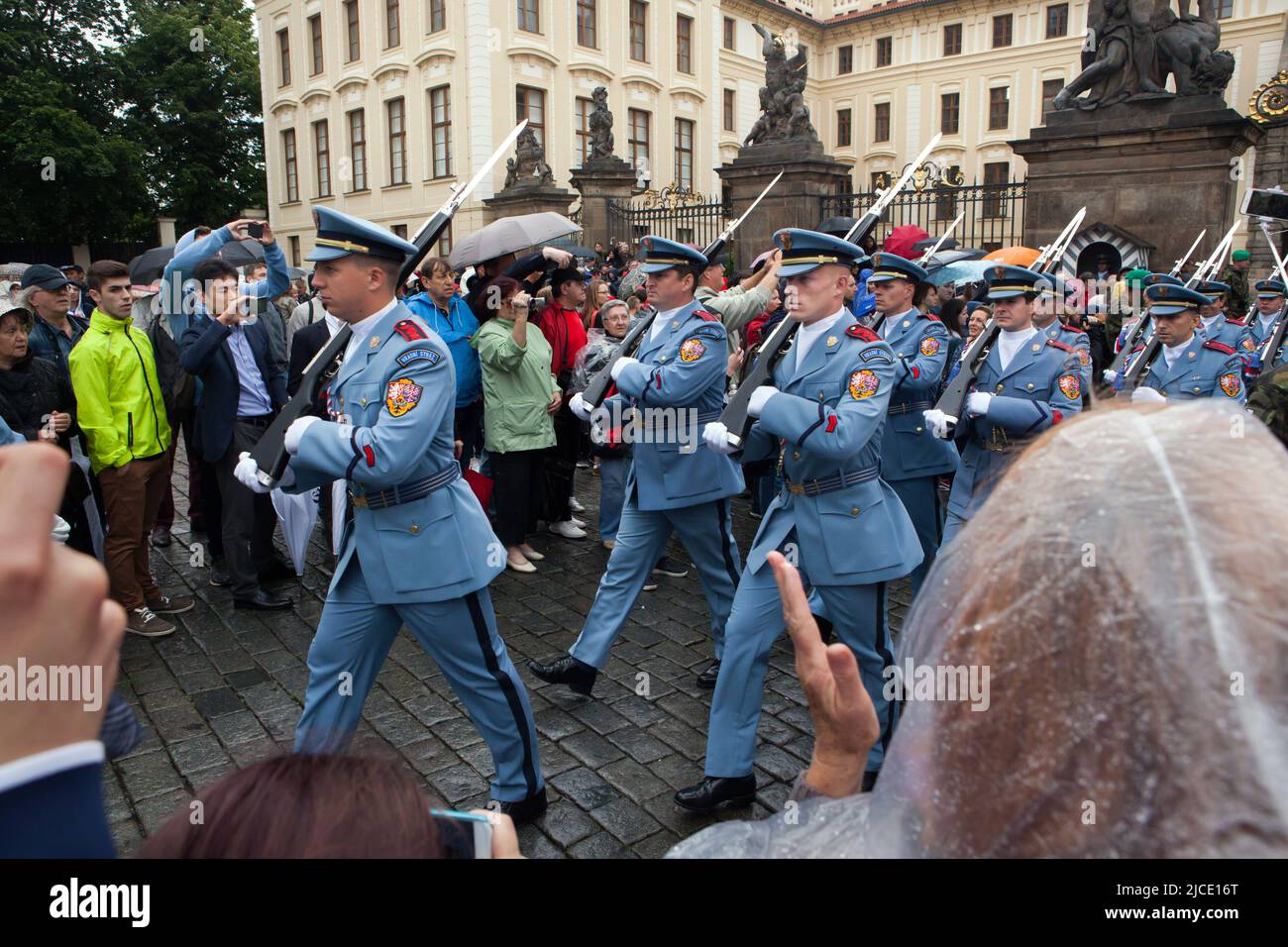 I turisti osservano la cerimonia del Cambio della Guardia del Castello (Hradní stráž) sotto la pioggia di fronte al Castello di Praga in Piazza Hradčanské a Praga, Repubblica Ceca. Foto Stock