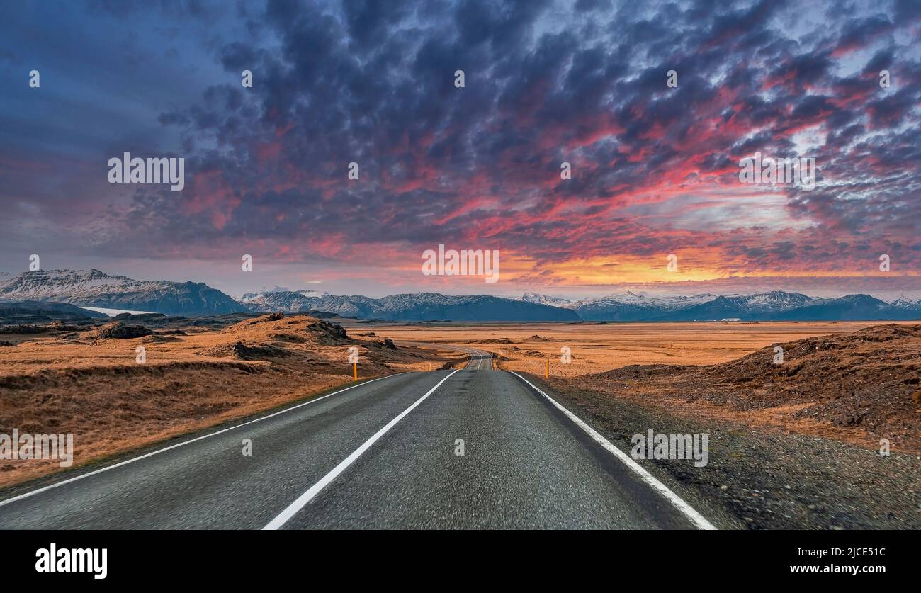 Strada vuota che svanisce in mezzo al paesaggio vulcanico contro il cielo nuvoloso durante il tramonto Foto Stock