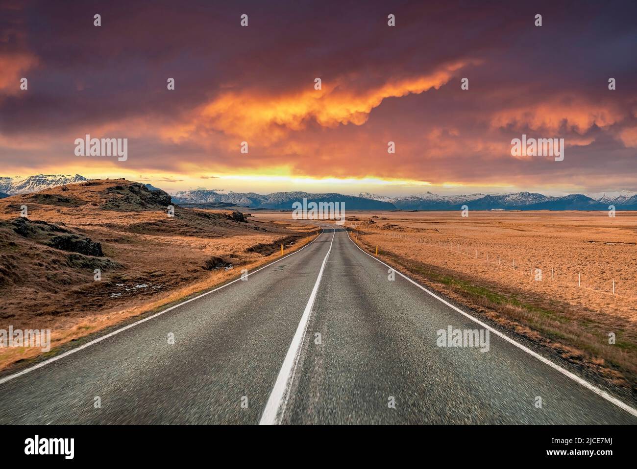 Strada vuota che svanisce in mezzo al paesaggio vulcanico contro il cielo drammatico al tramonto Foto Stock