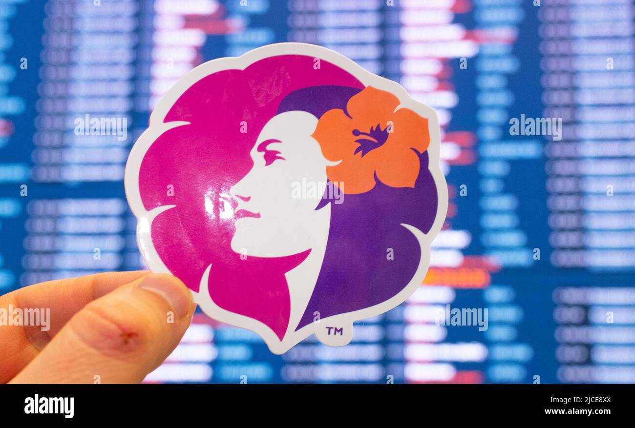 11 dicembre 2021, Honolulu, USA. L'emblema di Hawaiian Airlines sullo sfondo di un quadro di valutazione elettronico con orari di volo all'interno Foto Stock