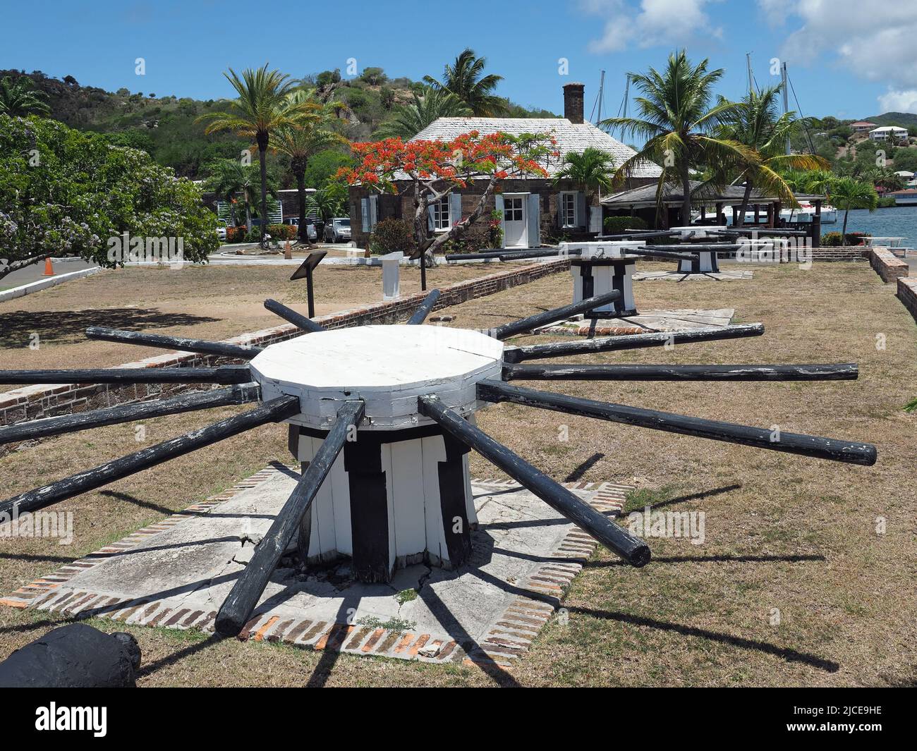 Vista di un vecchio cabestano al Nelson's Dockyard in English Harbour Antigua con la casa del capstan sullo sfondo Foto Stock