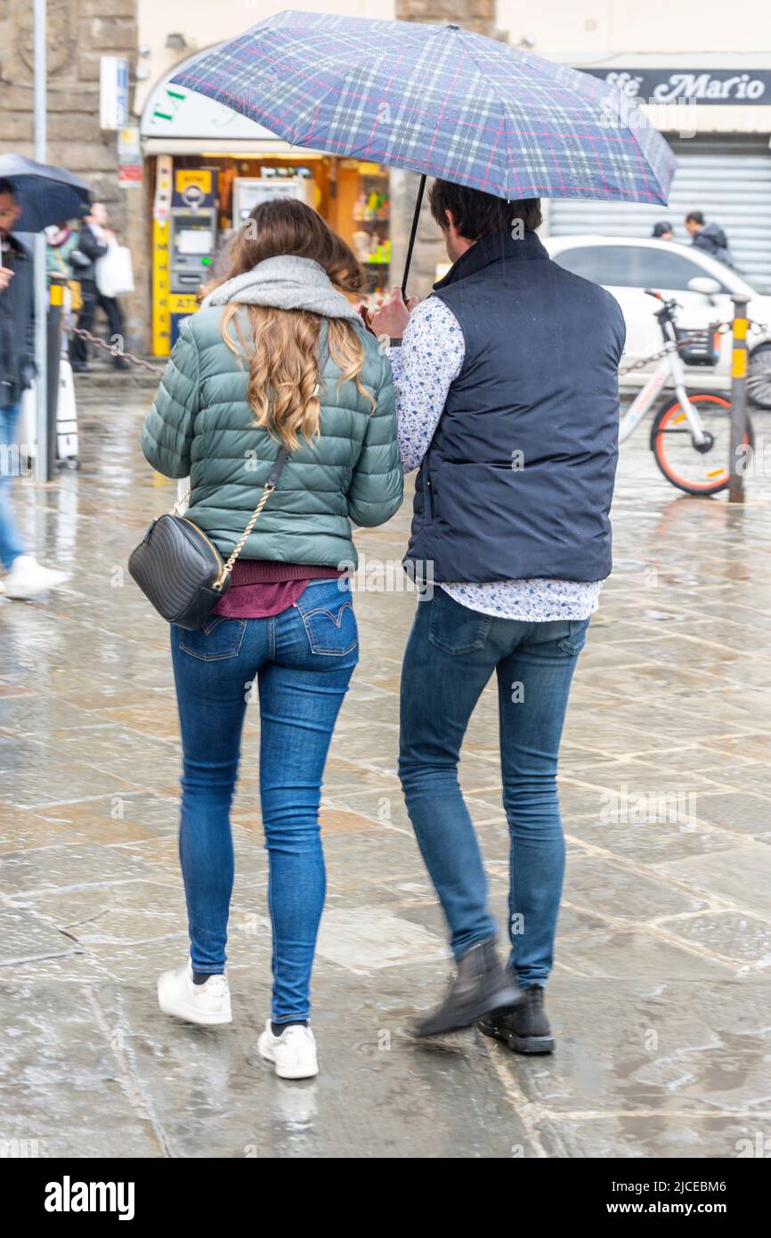 Giovane coppia che cammina sotto la pioggia con ombrellone, Piazza di Santa Croce, Firenze (Firenze), Regione Toscana, Italia Foto Stock