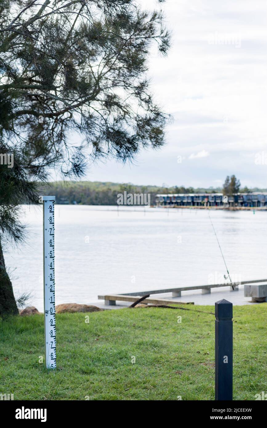 Un indicatore di profondità alluvione vicino alle cabine delle vacanze costruite lungo il bordo dell'acqua del Lago Conjola sul NSW, Costa Sud dell'Australia Foto Stock