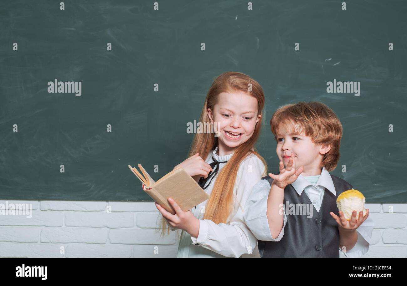 Il bambino sta imparando in classe sullo sfondo della lavagna. Bambini della scuola. Carino ragazzo piccolo preschool con bambina piccola in una classe. Schoolchild Foto Stock