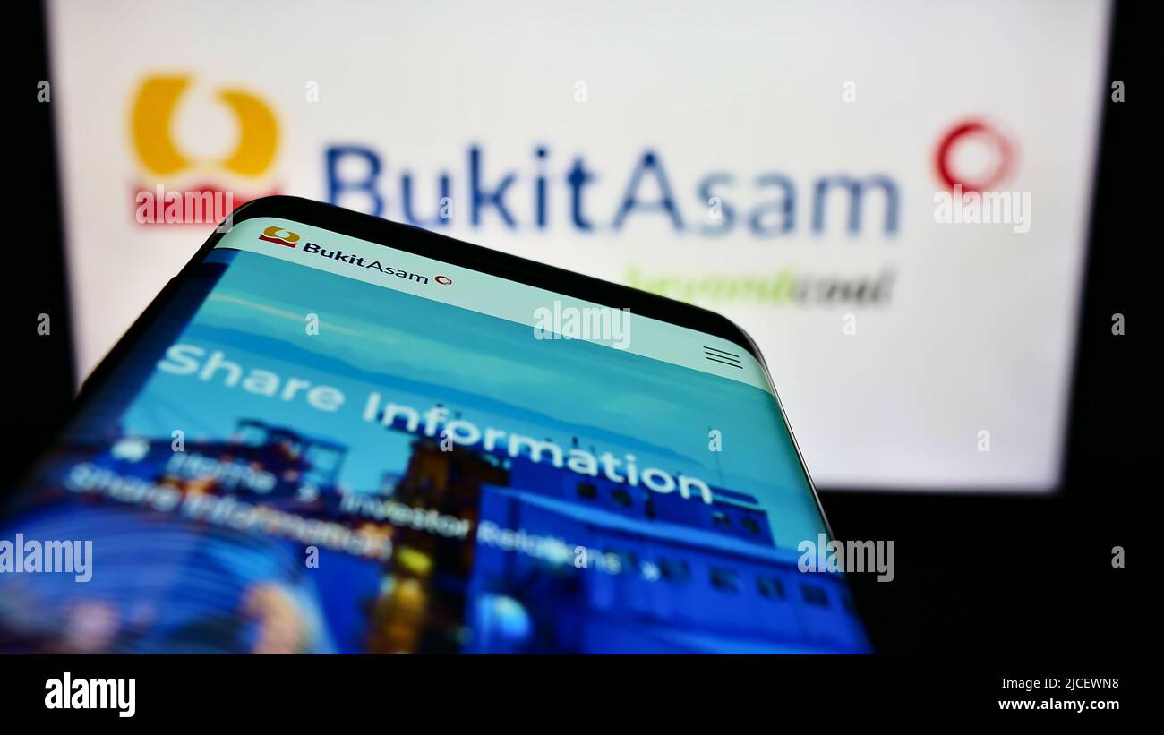 Smartphone con pagina web della società mineraria indonesiana PT Bukit Asam Tbk sullo schermo di fronte al logo aziendale. Mettere a fuoco sulla parte superiore sinistra del display del telefono. Foto Stock