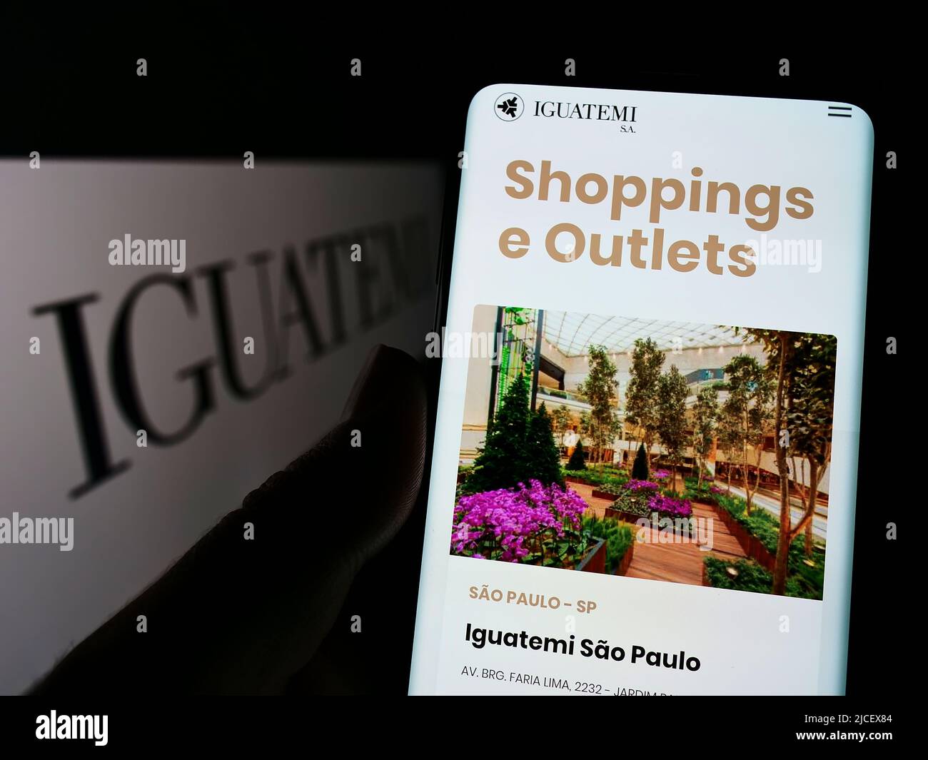 Persona che detiene il cellulare con pagina web della società Iguatemi Empresa de Shopping Centres SA su schermo con logo. Concentrarsi sul centro del display del telefono. Foto Stock