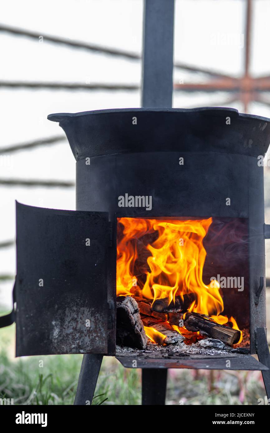 Cucinare cibo o pilaf in un calderone a fuoco. Cucina in calderone a fuoco aperto in natura. Bowler sul falò nella foresta. Primo piano fiamma fuoco. Spazio di copia. Foto Stock