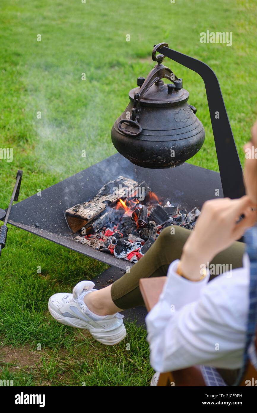 Gettare la pentola di ferro sul fuoco (vista da dietro la spalla) Foto Stock