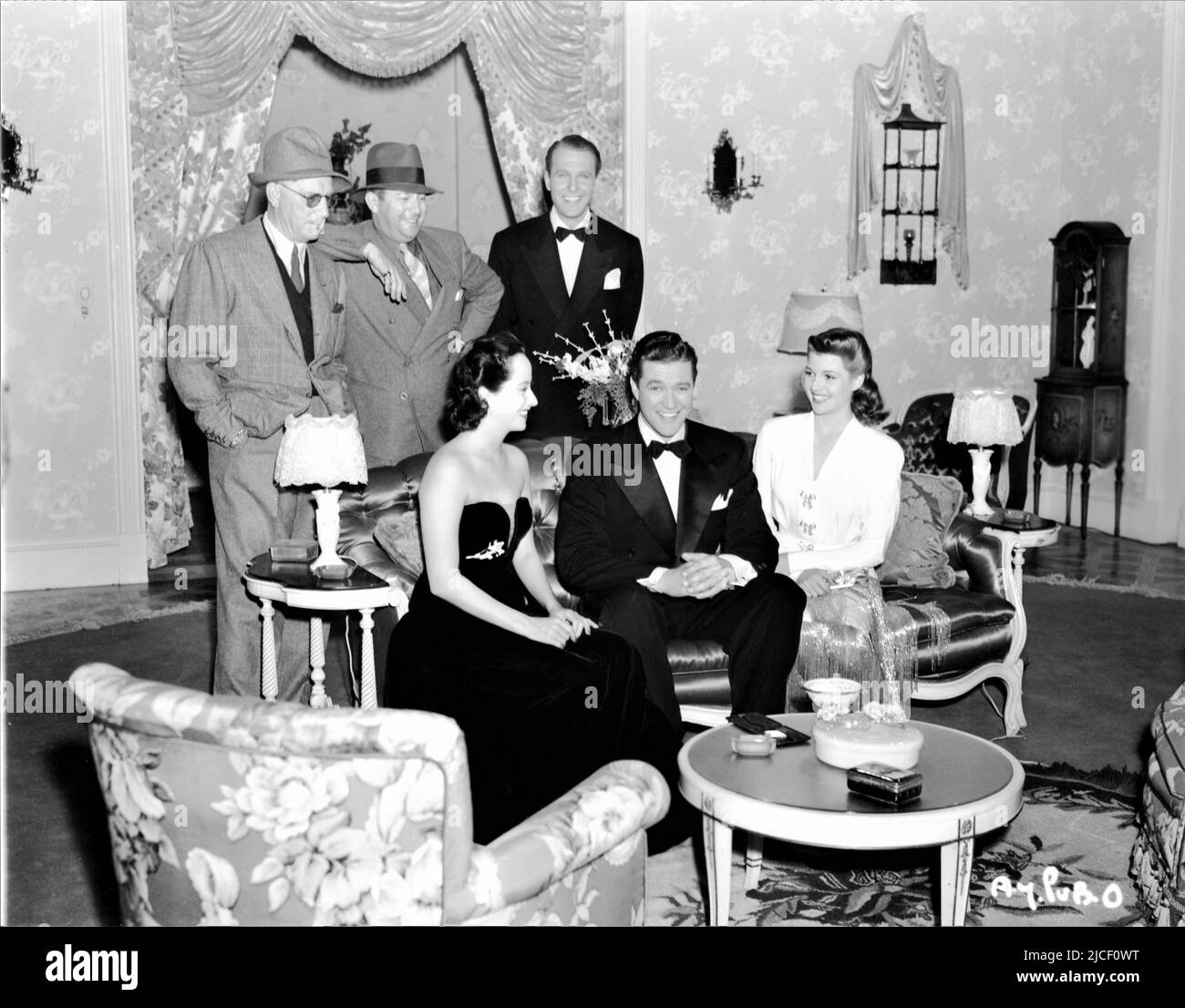 Direttore LLOYD BACON associato Produttore MARK HELLINGER e RALPH BELLAMY in piedi e seduto MERLE OBERON DENNIS MORGAN e RITA HAYWORTH sul set candid durante le riprese del SUO 1941 direttore LLOYD BACON abiti Orry-Kelly Warner Bros.. Foto Stock