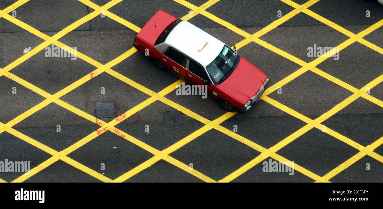 Guardando giù sui taxi di Hong Kong che attraversano un incrocio nel distretto centrale di Hong Kong. Foto Stock