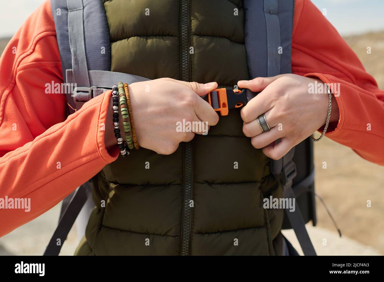 Scatto ritagliato di turista femminile irriconoscibile in piedi all'aperto regolazione cintura toracica su zaino da trekking Foto Stock