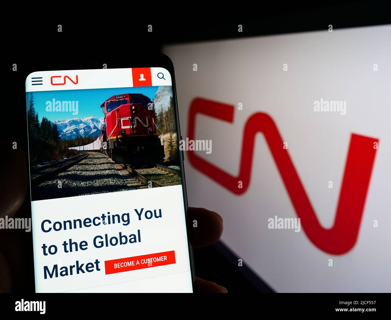 Persona che tiene il cellulare con il sito web della Canadian National Railway Company (CN) sullo schermo di fronte al logo. Concentrarsi sul centro del display del telefono. Foto Stock