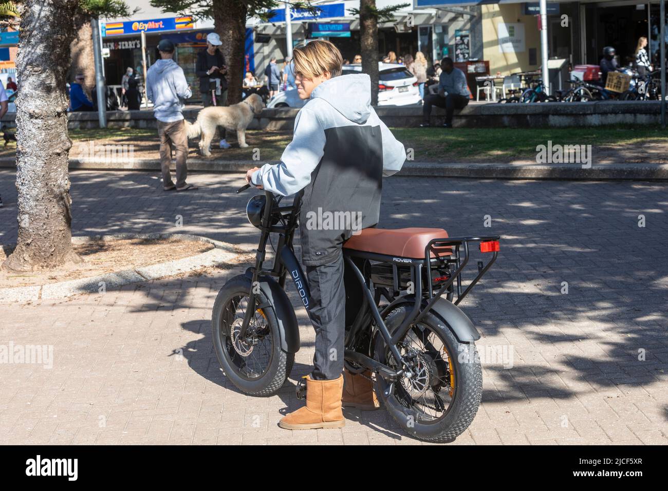 Ragazzo australiano adolescente in sella a una bicicletta elettrica Dirodi Rover a Manly Beach Sydney, questa bicicletta elettrica ha pneumatici grassi e un grande sedile per due persone Foto Stock