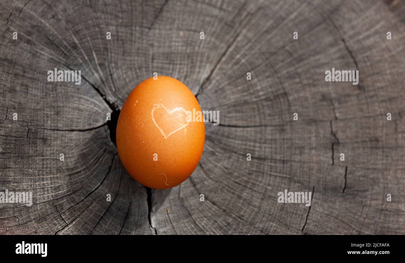 Uovo con cuore su un tavolo di legno Foto Stock