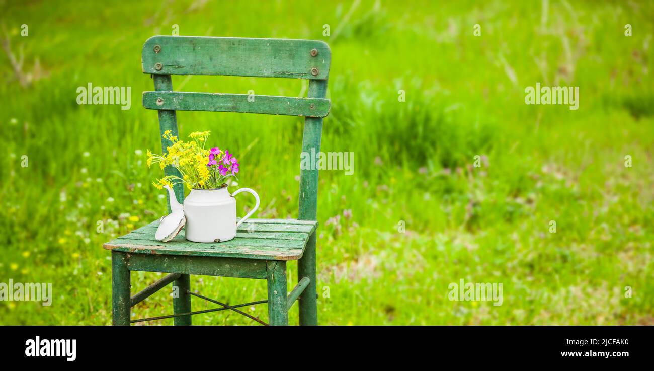Decorazione con una vecchia sedia e una caffettiera in un giardino naturale Foto Stock