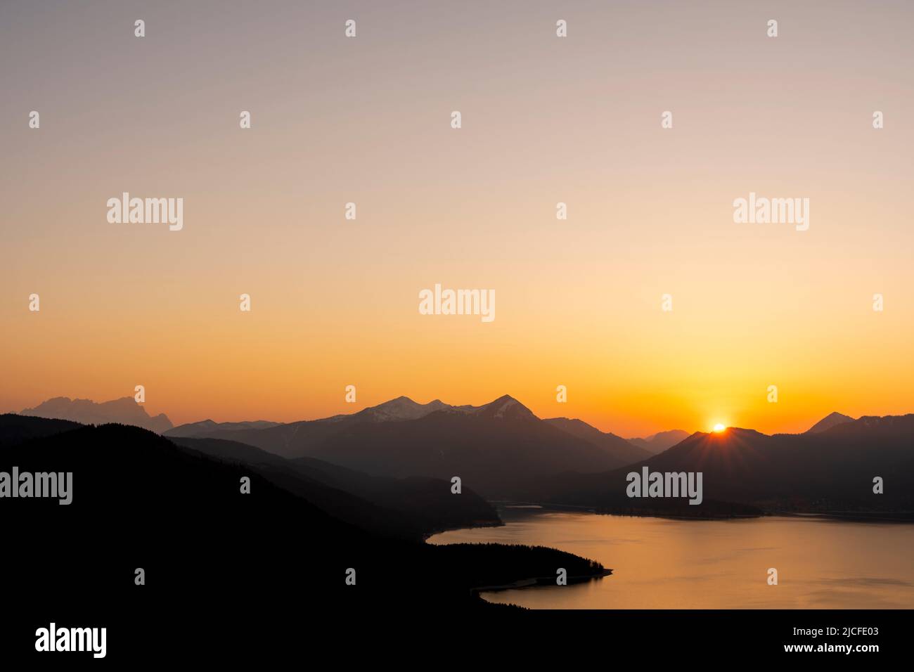 Tramonto senza nuvole con cielo notturno arancione sul Walchensee, sullo sfondo il Simetsberg, l'Estergebirge e molto a sinistra lo Zugspitze. Foto Stock