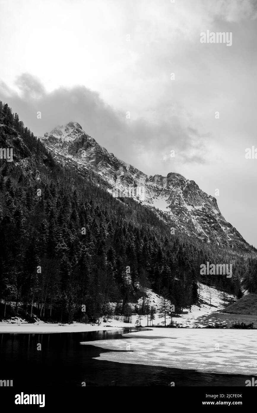 Ghiaccio spezzato a Ferchensee nelle Alpi bavaresi sopra Mittenwald all'inizio della primavera. Sullo sfondo le montagne di Wetterstein con nubi dense e neve fresca. Foto Stock