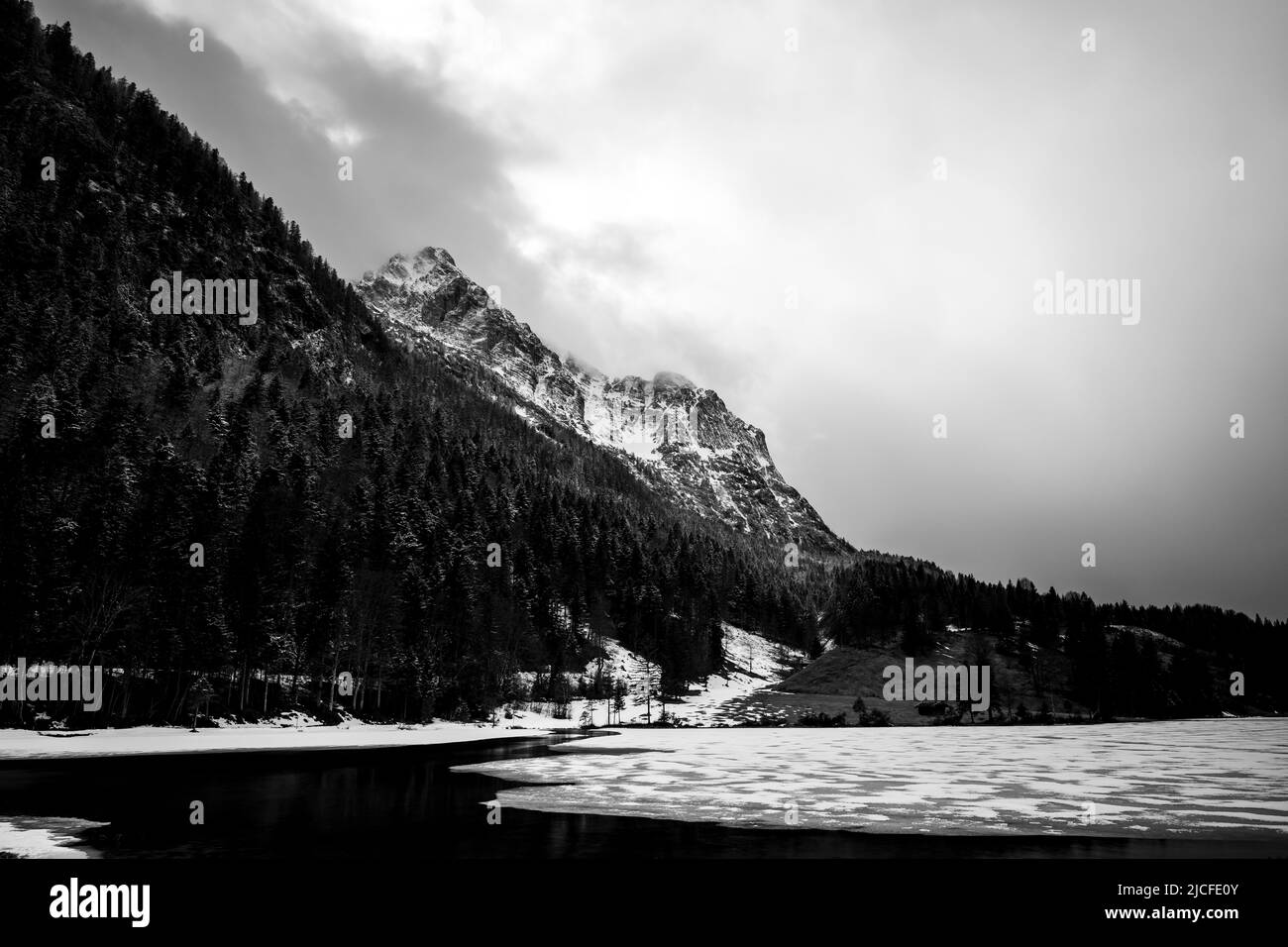 Ghiaccio spezzato a Ferchensee nelle Alpi bavaresi sopra Mittenwald all'inizio della primavera. Sullo sfondo le montagne di Wetterstein con nubi dense e neve fresca. Foto Stock