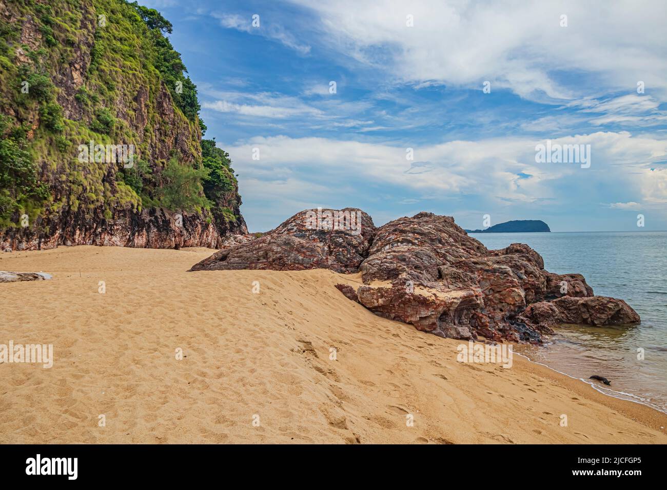 Paesaggio sul mare con formazioni rocciose e vegetazione ricoperte di scogliere rocciose sulla spiaggia di Pantai Dendong nel distretto di Besut di Terengganu, Malesia. Foto Stock