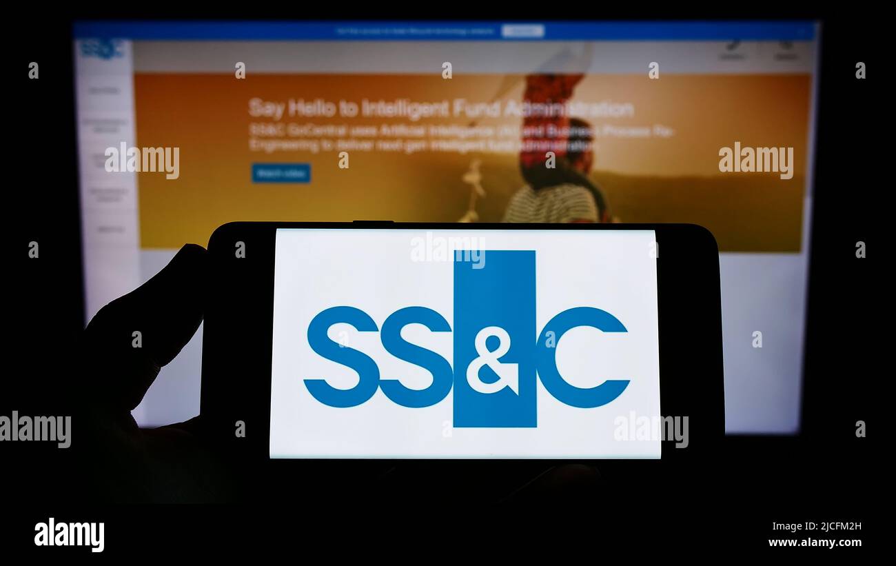 Persona che tiene uno smartphone con il logo della società statunitense SSC Technologies Holdings Inc. Sullo schermo di fronte al sito Web. Mettere a fuoco sul display del telefono. Foto Stock