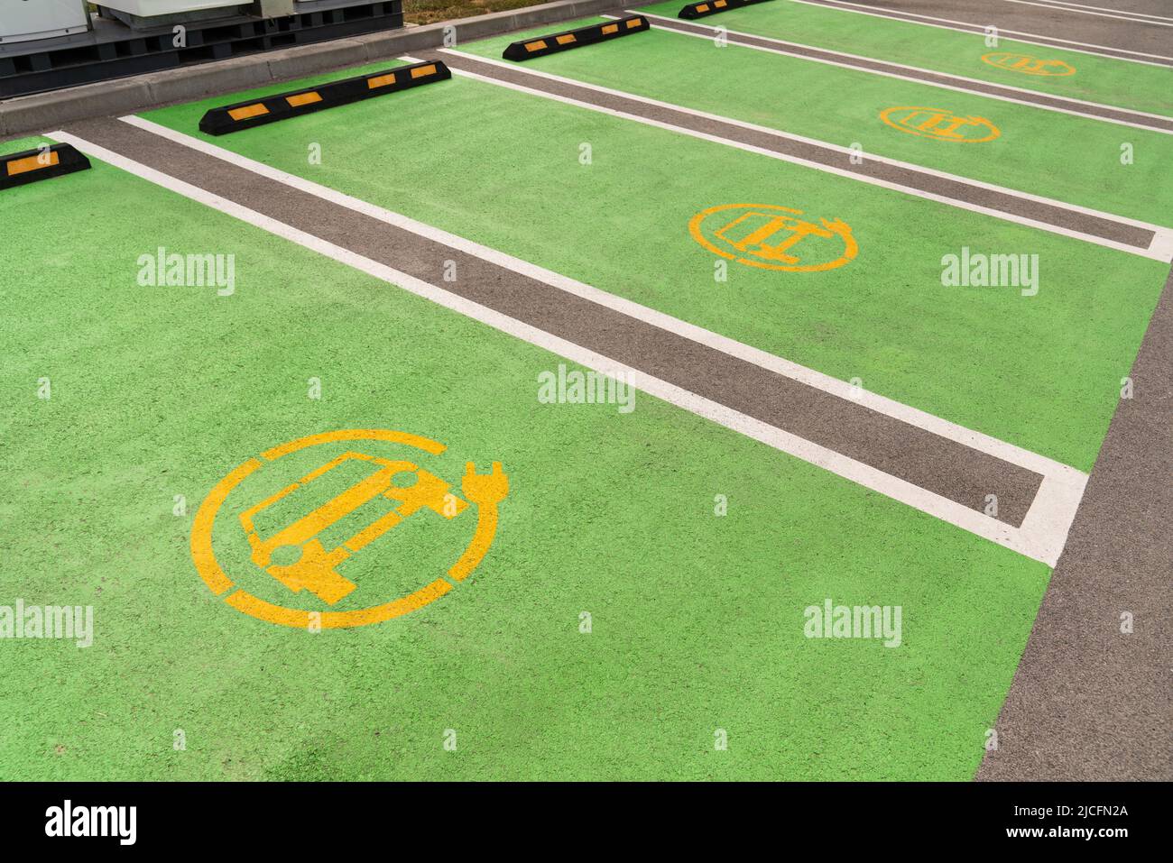 Simbolo giallo dell'auto elettrica su asfalto verde. Parcheggio a pagamento per veicoli elettrici Foto Stock