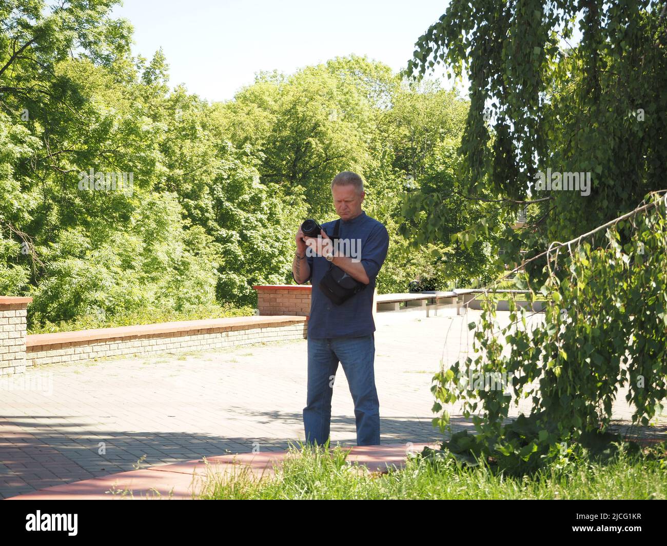 Fotografo. Un uomo con una macchina fotografica in mano sulla strada, scattando foto. Foto Stock