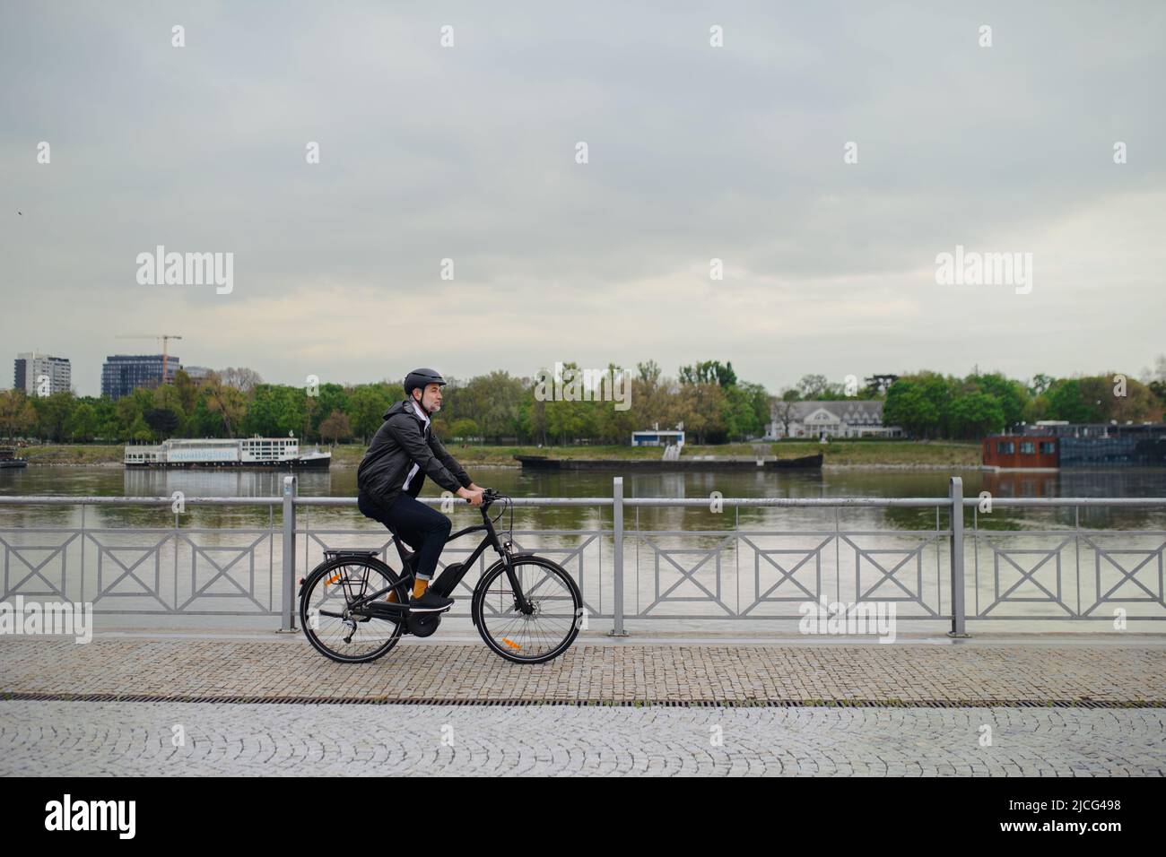Uomo d'affari commuter sulla strada per il lavoro, in bicicletta sul ponte, concetto di stile di vita sostenibile. Foto Stock