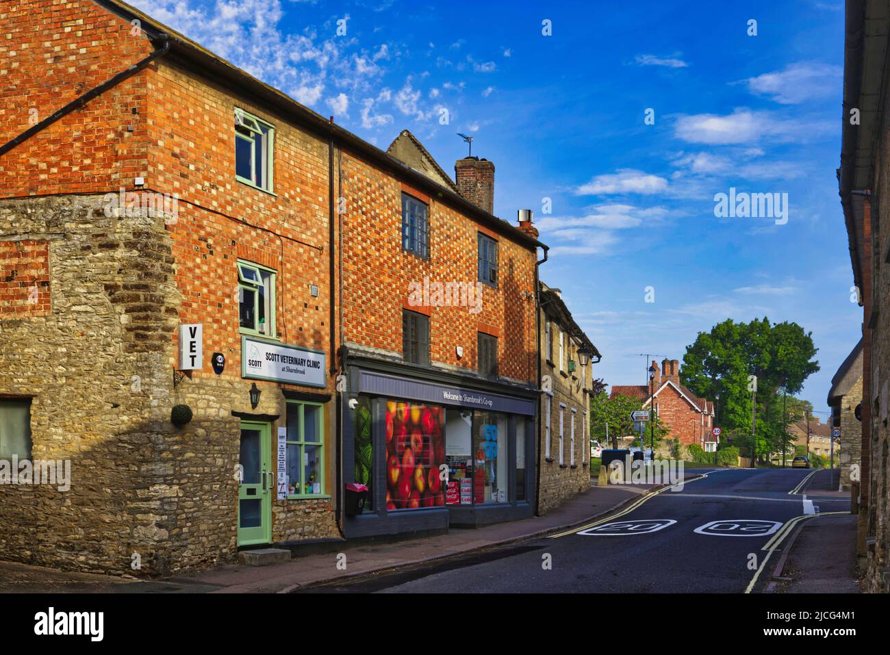 Sharnbrook, Bedfordshire, Inghilterra, Regno Unito - Co-op negozio, clinica veterinaria e cottage nel villaggio in alta strada in una mattinata di sole Foto Stock
