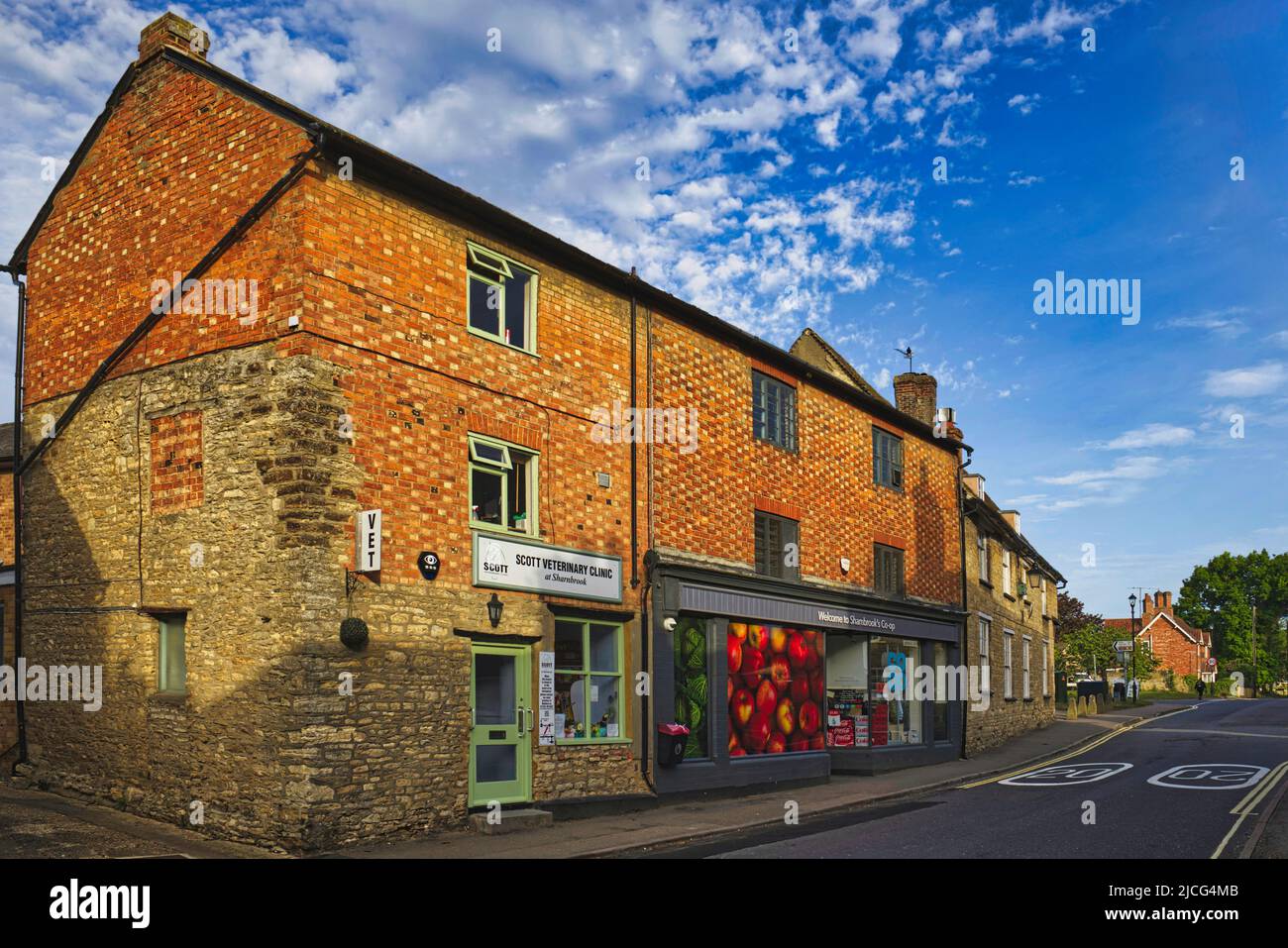 Sharnbrook, Bedfordshire, Inghilterra, Regno Unito - Co-op negozio, clinica veterinaria e cottage nel villaggio in alta strada in una mattinata di sole Foto Stock