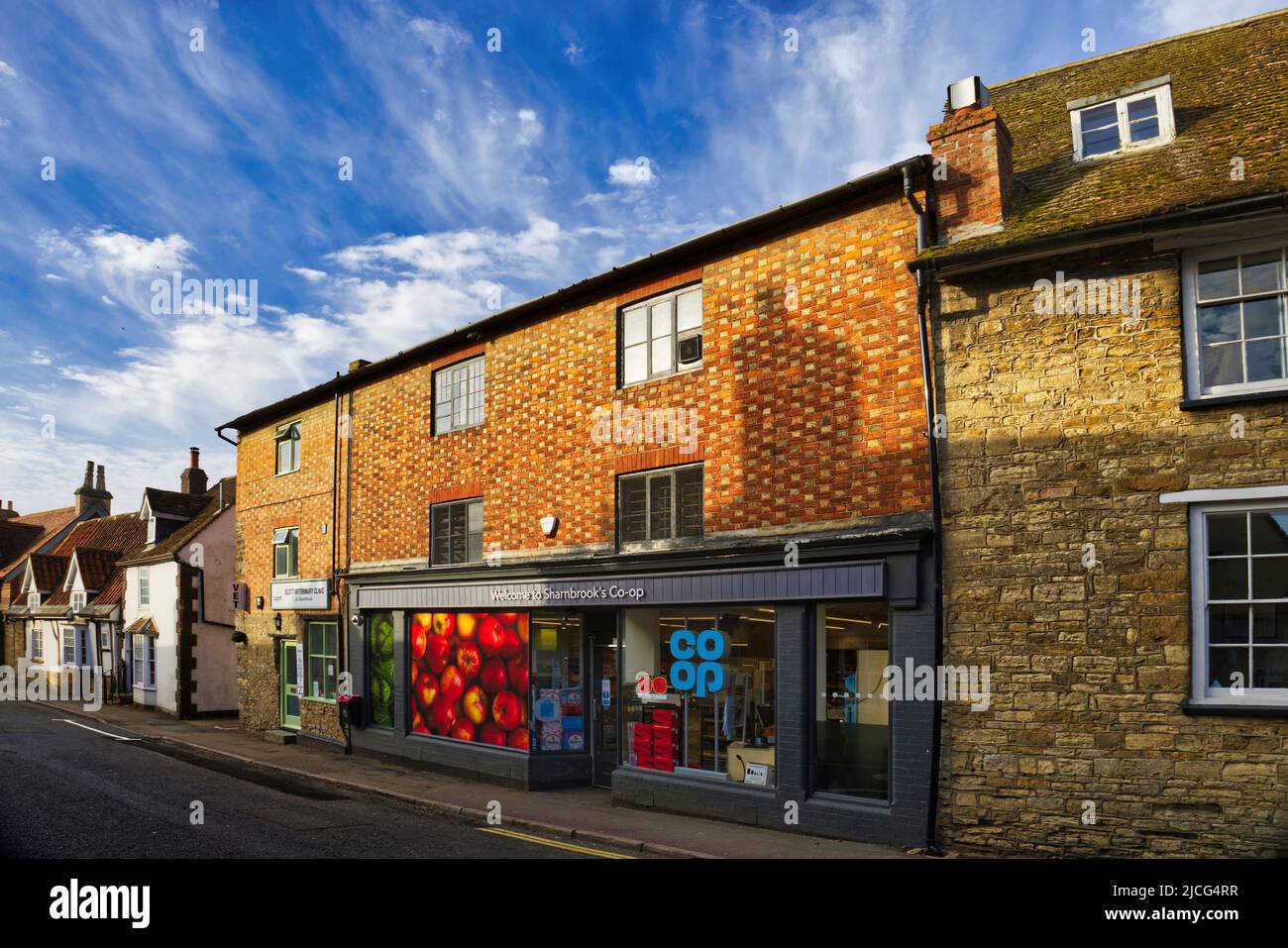 Sharnbrook, Bedfordshire, Inghilterra, Regno Unito - Co-op negozio, clinica veterinaria e cottage nel villaggio in alta strada in una mattinata di sole Foto Stock