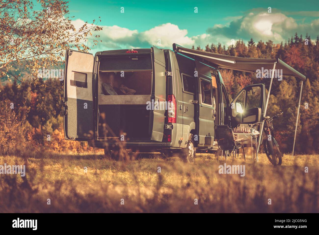 Famiglia Camper con tenda parcheggiata in un luogo tranquillo circondato dalla natura. Tutte le porte del furgone sono aperte, una Mountain Bike si trova all'ingresso laterale. Scacchi Foto Stock