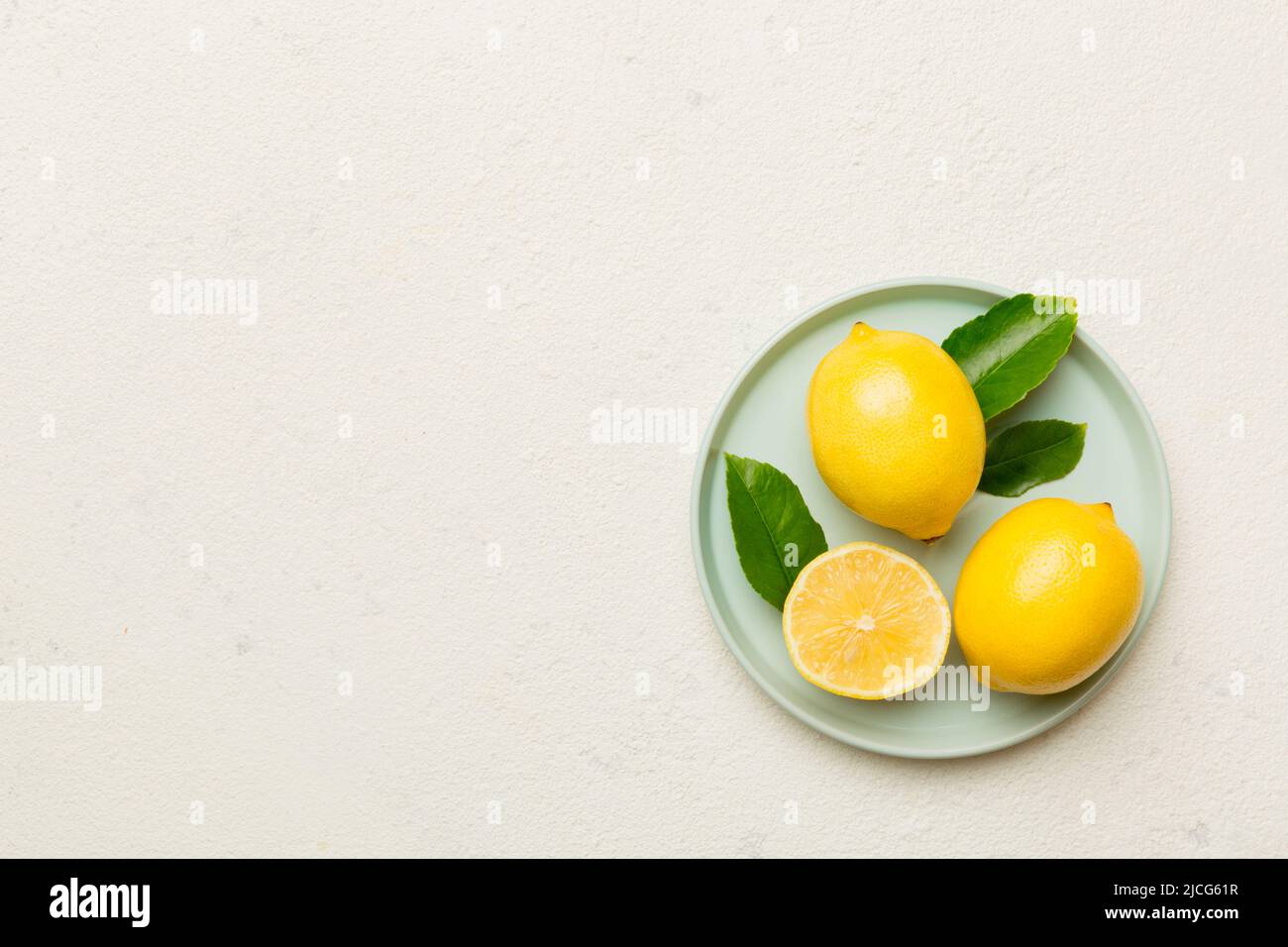 Limone tagliato fresco e limoni interi su piatto rotondo su sfondo colorato. Cibo e bevande ingredienti preparazione. Tema di cibo sano vista dall'alto Vith c Foto Stock