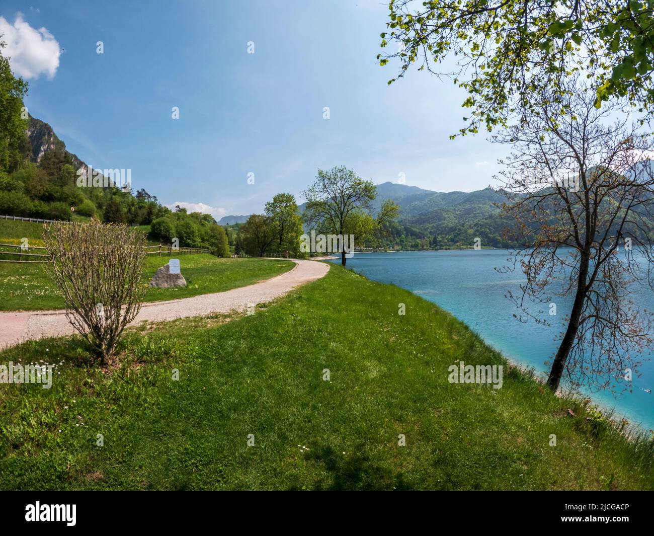 Il Lago di Ledro è un lago di montagna con acqua verde e erba di ciglio verde in una giornata estiva in Trentino, nel nord Italia Foto Stock