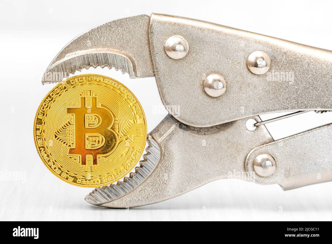 Divieto di estrazione e commercio di bitcoin. Commercio illegale di bitcoin. Controllo sullo scambio di criptovalute. Tecnologia Blockchain. Moneta Bitcoin in pinze. Foto Stock