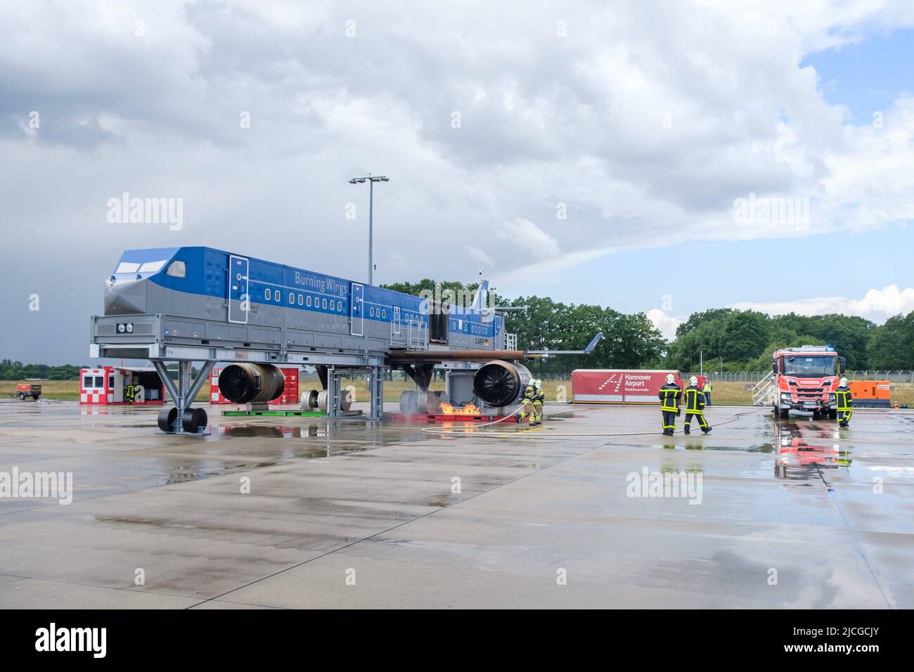 Langenhagen, Germania. 13th giugno 2022. I vigili del fuoco dell'aeroporto spengono un incendio a turbina all'aeroporto di Hannover durante un esercizio presso la struttura mobile di simulazione del fuoco. Lo stabilimento è un progetto congiunto degli aeroporti di Hannover, Stoccarda e Brema ed è destinato a servire la formazione e l'esercizio dei vigili del fuoco degli aeroporti. Credit: OLE Spata/dpa/Alamy Live News Foto Stock