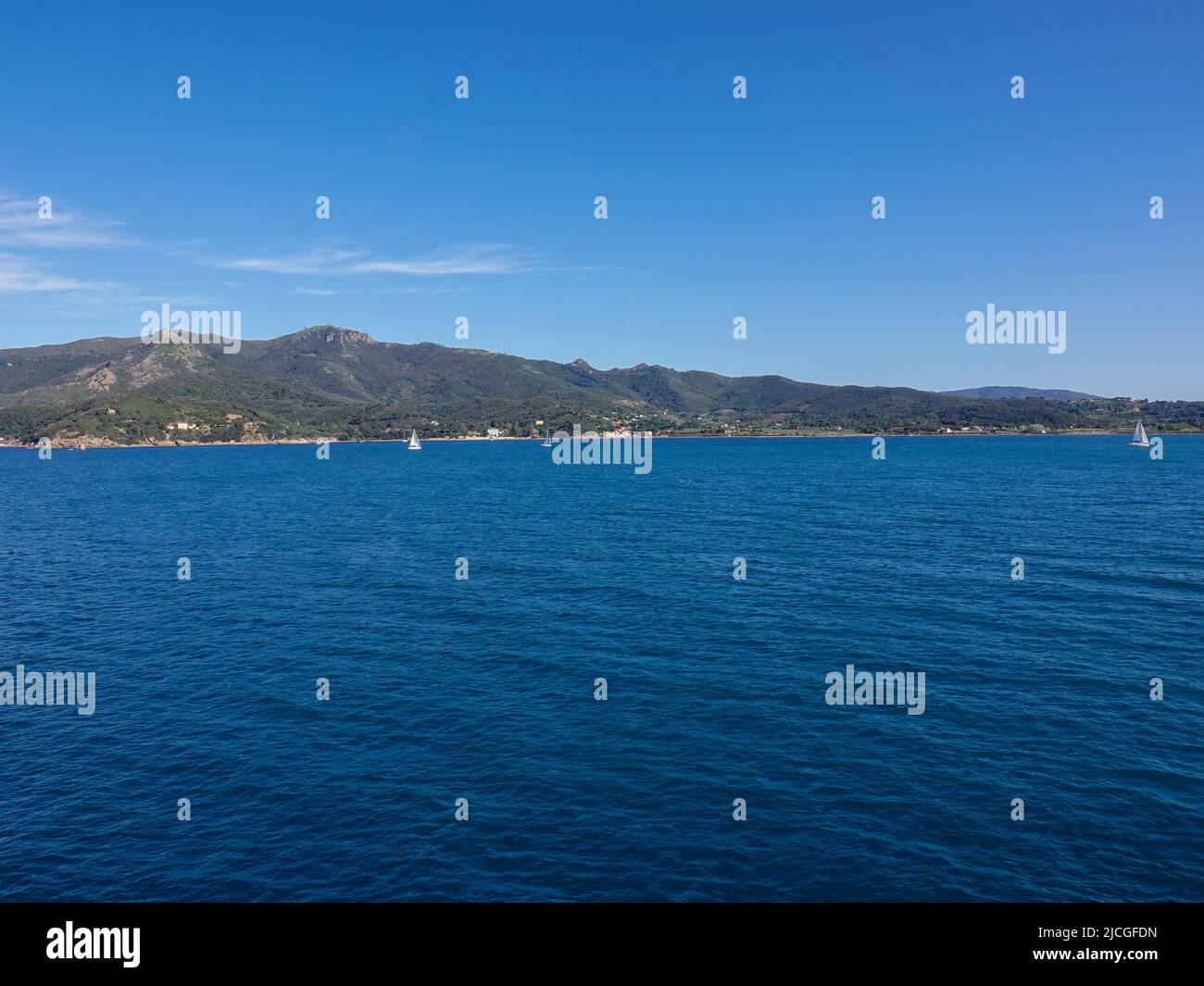 Barche a vela al largo della costa d'Elba vicino alla città di Portoferraio visto dal Mar Ligure nell'Arcipelago Toscano, Italia. Foto Stock