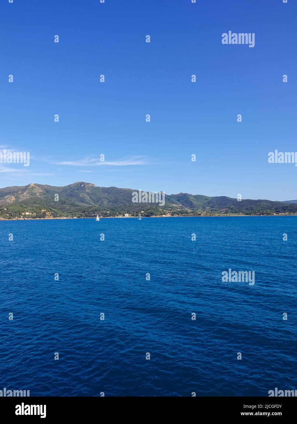 Barche a vela al largo della costa d'Elba vicino alla città di Portoferraio visto dal Mar Ligure nell'Arcipelago Toscano, Italia. Foto Stock