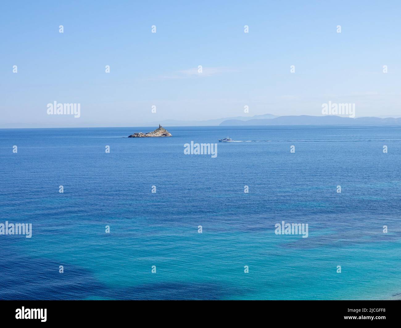 Barca che passa il faro dello Scoglietto arroccato su una roccia nel Mar Ligure, vista dall'isola d'Elba, provincia di Livorno, Italia. Foto Stock