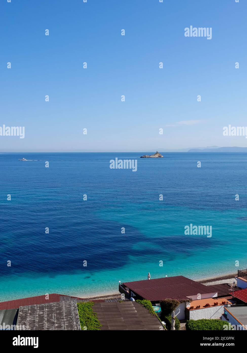 Barca che passa il faro dello Scoglietto arroccato su una roccia nel Mar Ligure, vista dall'isola d'Elba, provincia di Livorno, Italia. Foto Stock