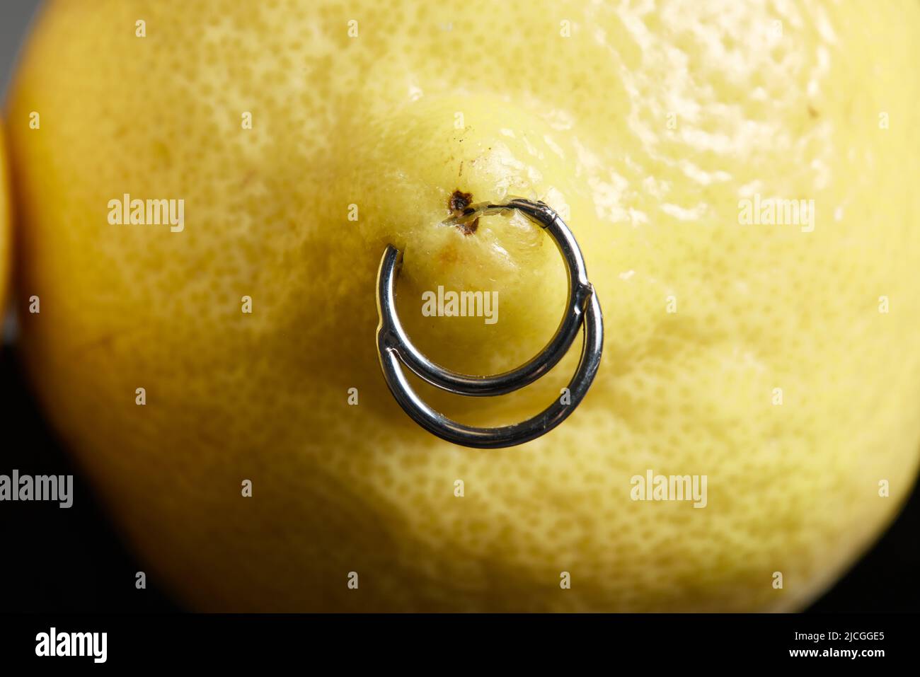 piercing orecchini in un limone su sfondo Foto Stock