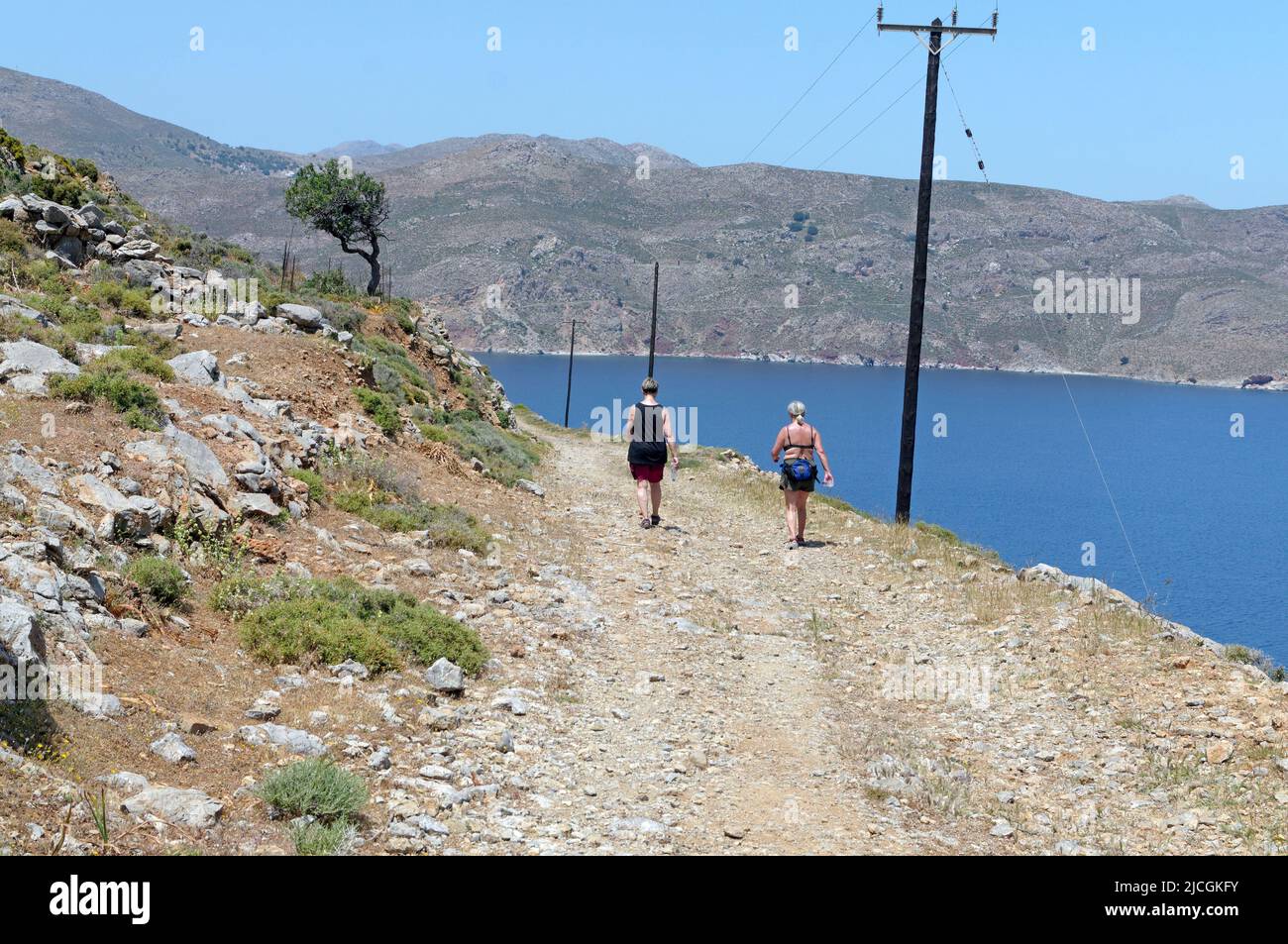 Due donne che camminano su un sentiero aspro e polveroso sull'isola di Tilos, vicino a Rodi, camminando verso Livadia. Primavera 2022. Maggio Foto Stock