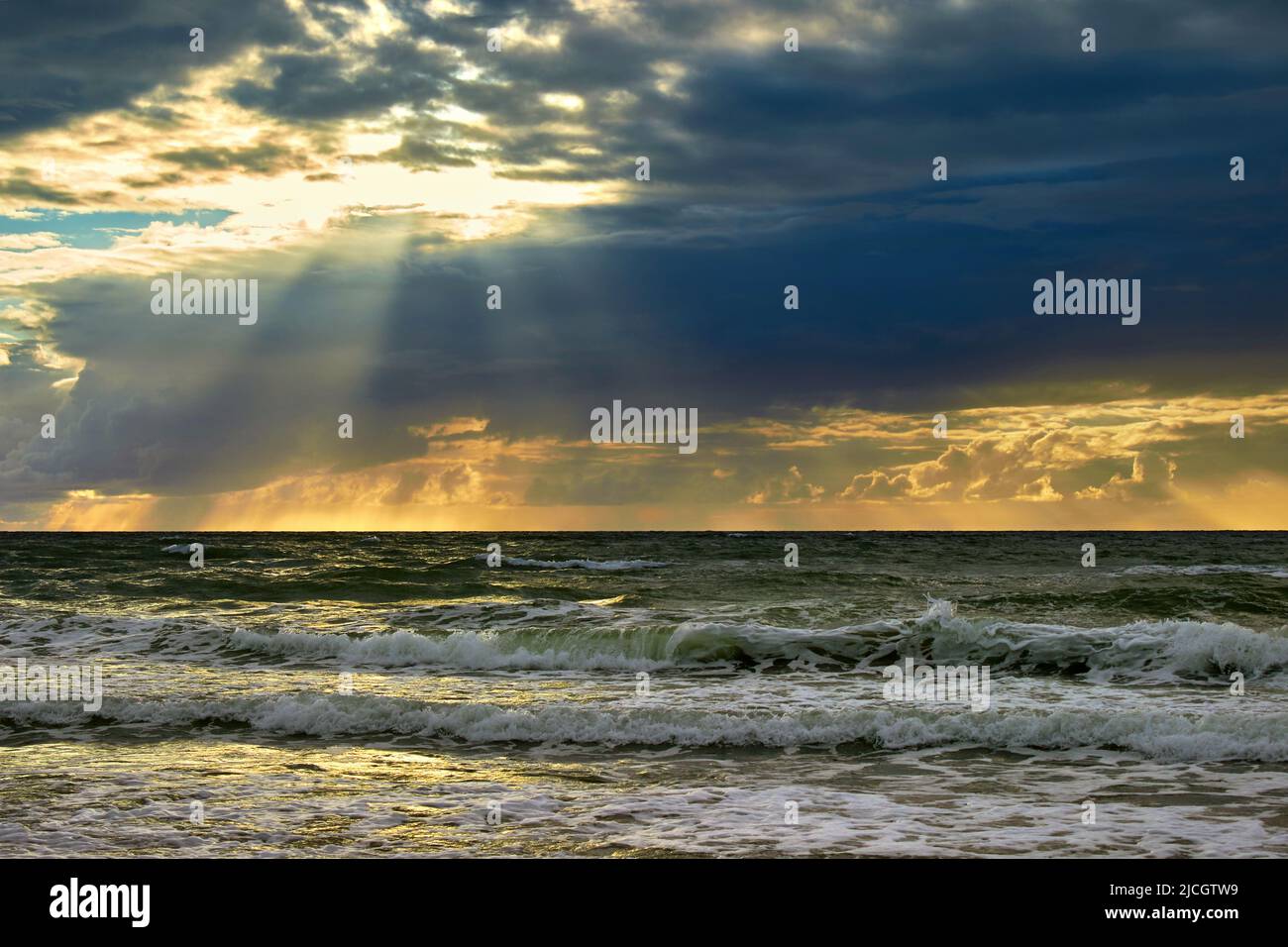 Il mare e i raggi del sole fanno il loro senso attraverso le nuvole. Tramonto sul Mar Baltico Foto Stock