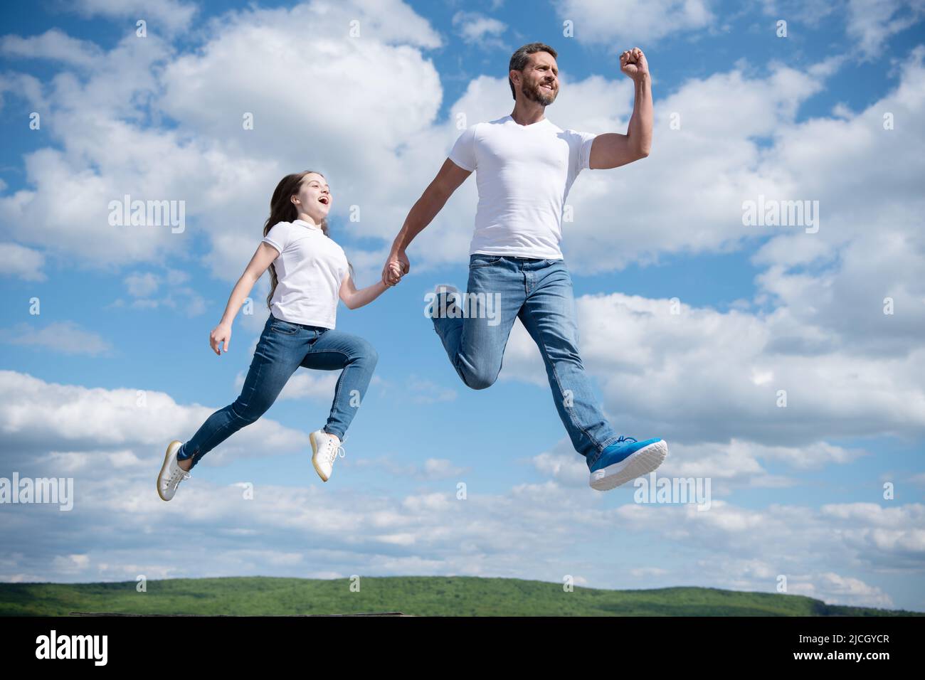 felice padre e figlia saltano in cielo. amicizia Foto Stock