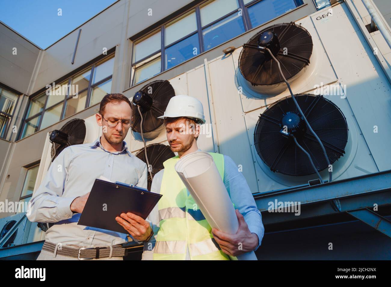 Tecnici dell'assistenza nell'ispezione uniforme del sistema di refrigerazione industriale, ispezione di impianti di refrigerazione esterni Foto Stock