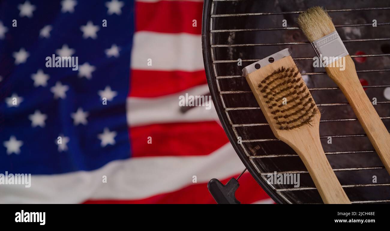 Diversi strumenti su griglia barbecue sullo sfondo della bandiera americana con spazio per la copia Foto Stock