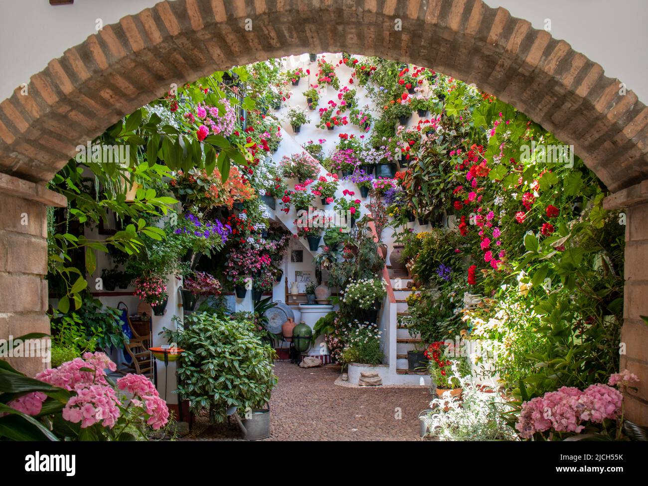 Arco de entrada a un patio rodeado de flores en primavera, Córdoba, España Foto Stock