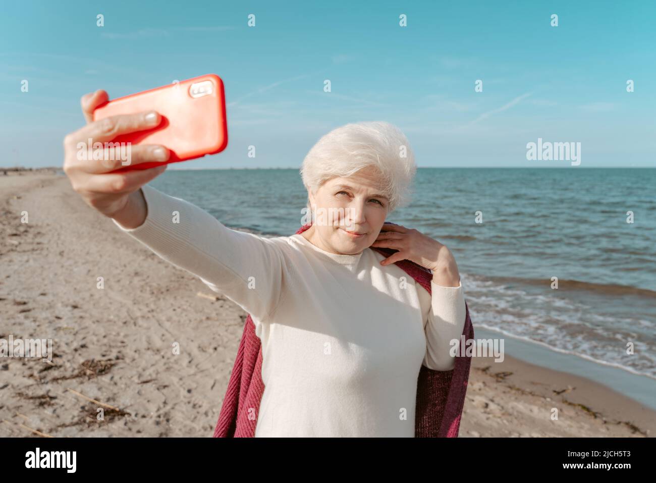 Signora sicura che prende selfie sulla spiaggia Foto Stock