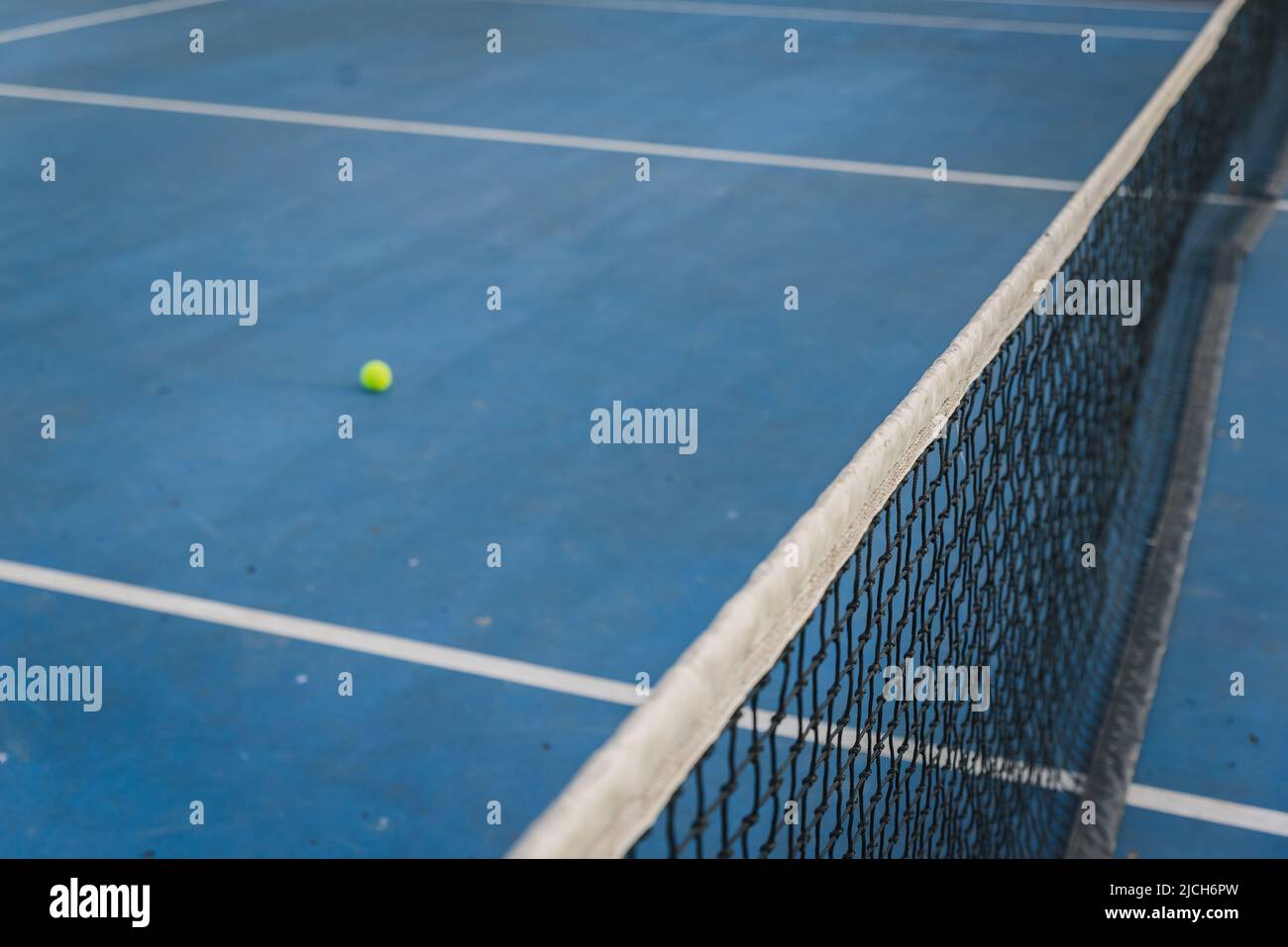 Rete da tennis e palla attraverso un campo blu. Foto Stock