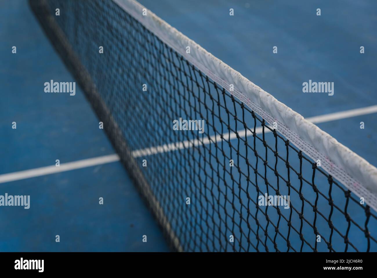 Primo piano di rete da tennis in nylon su un campo blu. Foto Stock